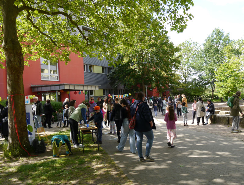 Menschen auf dem Schulhof beim Schulfest