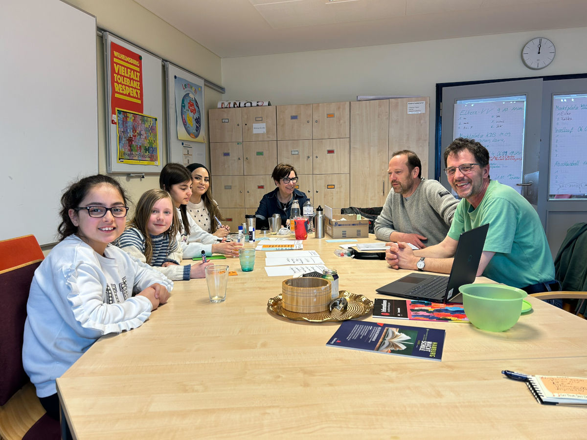 Die Arbeitsgruppe Homepage bei der Arbeit im Menschenzimmer an einem gro&szlig;en Tisch mit Moderationskarten, Tablet und Laptop